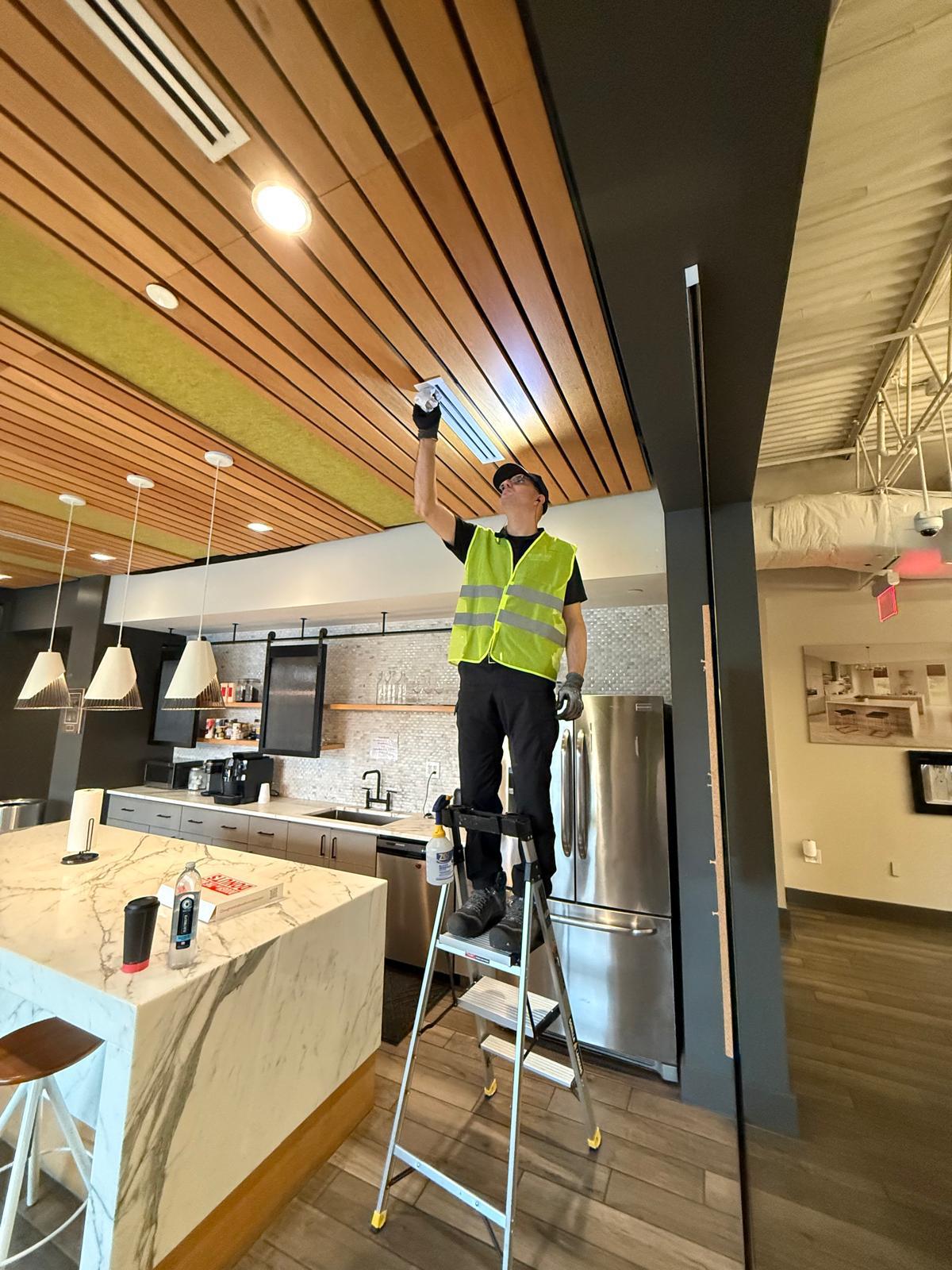 Corporate break room — linear diffuser cleaning above the kitchen island and prep counter